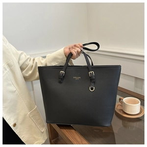 Detail of black cross-grain tote bag with gold brand lettering and adjustable strap