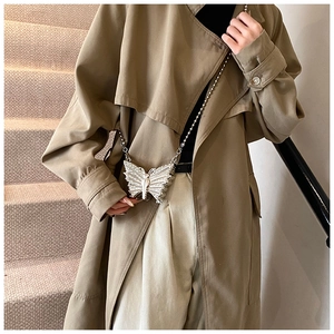 Sac papillon argenté élégant avec cristaux porté par un mannequin dans un décor beige