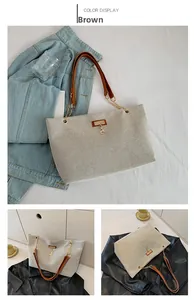 Detail of grey woven tote bag with brown leather handles and gold metal chain hardware