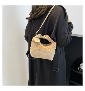 Close-up of beige plush faux fur handbag featuring leather handle and fashion tag