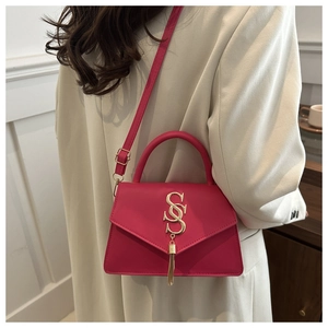 Detail of rose pink leather shoulder bag featuring gold SS metal logo and elegant tassel