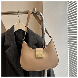 Detail of beige crescent underarm bag with gold clasp on a minimalist coat