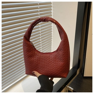 Close-up of deep red woven leather tote bag with unique knot detail and silver zipper