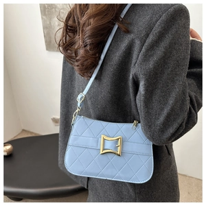 Détail du sac bandoulière matelassé bleu clair avec boucle dorée sur un modèle