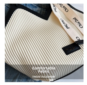 Detail of off-white vertical pleated fabric tote bag with black leather logo patch