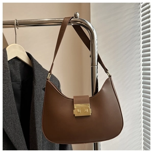 Detail of a brown crescent hobo bag with gold metal buckle and smooth leather texture