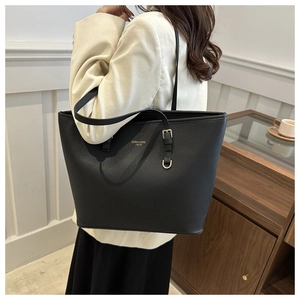 Detail of a large black tote bag with gold lettering and adjustable shoulder strap