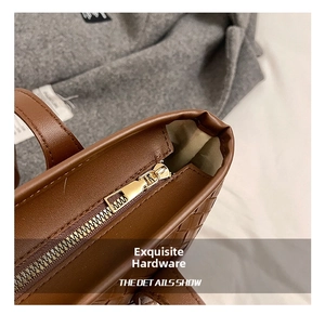 Detail view of smooth metal zipper and woven texture on dark brown tote bag