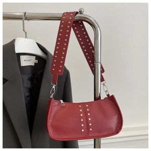 Détail du sac rouge en cuir litchi avec rivets argentés et finitions métalliques