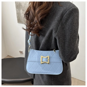 Détail d'un sac bandoulière matelassé bleu clair avec boucle dorée et fine lanière