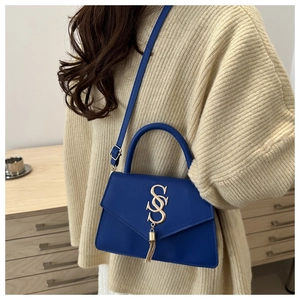 Detail of dark blue leather crossbody bag featuring gold double S logo and tassel fringe