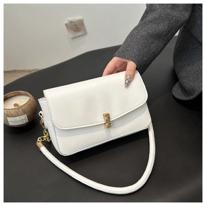 Detail view of the white minimalist underarm bag with gold metal lock and wide shoulder strap