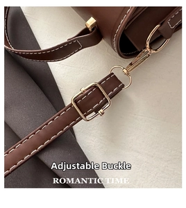 Detail of adjustable golden buckle on brown leather bag with white contrast stitching