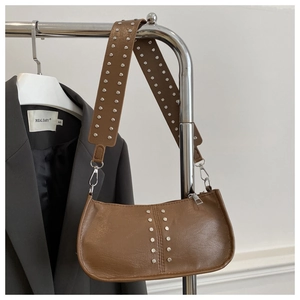 Détail d'un sac sous le bras en cuir marron avec des clous argentés et texture métallique