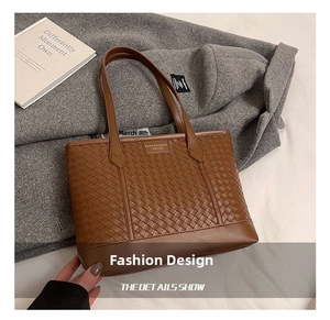 Detail of brown woven leather tote bag featuring fine texture and top handle design