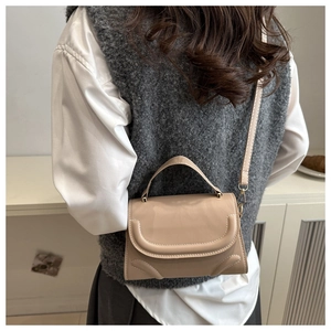 Detail of elegant apricot leather handbag with curved stitching and adjustable strap