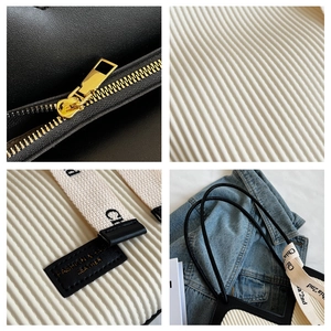 Macro details of vertical stripe tote bag showing metal zipper and woven strap texture