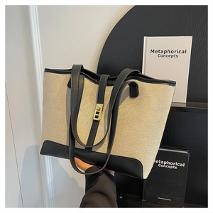Détail du cabas contrasté en toile blanc cassé et cuir noir avec fermoir doré métallique