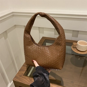Brown woven hobo tote bag with knotted handle and zipper closure on a table