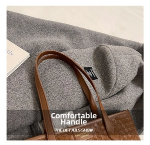 Detailed view of brown woven tote bag featuring gold lettering and smooth leather handles