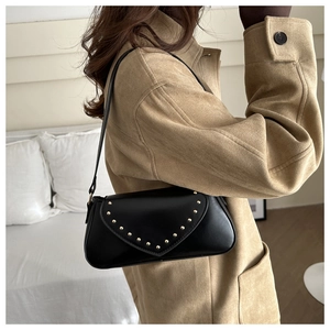 Detail view of black PU leather crescent bag with golden V-shaped rivets on shoulder