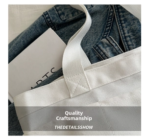 Close-up of reinforced stitching on the shoulder straps of a white canvas tote bag