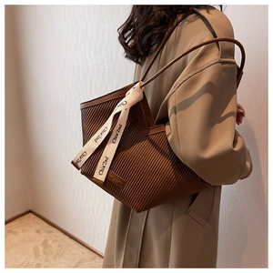 Detailed close-up of brown pleated tote bag with branded ribbon and soft texture