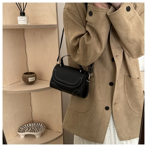 Detail of black square handbag with white contrast stitching and gold hardware