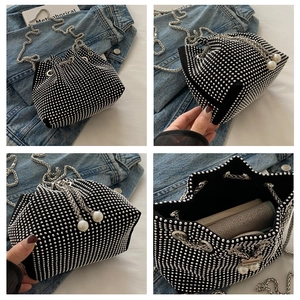 Detailansicht der Mini-Eimertasche in Schwarz mit Nieten, Perlenzugband und Kettenriemen