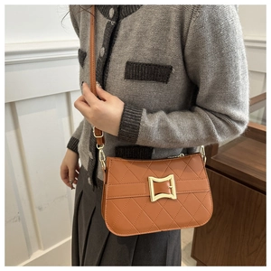 Sac à bandoulière matelassé marron avec boucle dorée porté par un mannequin chic