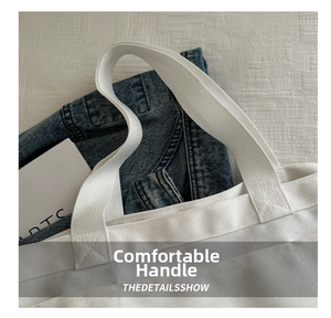 Close-up of durable reinforced stitching on thick canvas straps of a white tote bag