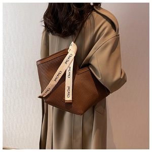 Detail of brown pleated tote bag with canvas straps and unique vertical texture
