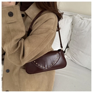 Detail view of vintage dark brown PU leather shoulder bag with gold rivet accents