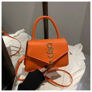 Close-up of bright orange shoulder bag with V-shaped flap and gold S-shaped tassel detail