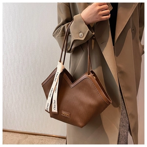 Detail of a brown pleated tote bag featuring a V-shaped opening and silk scarf handle