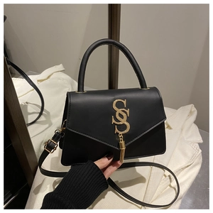 Detail of black faux leather bag with gold cross-letter hardware and tassel pendant