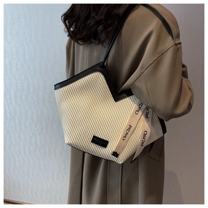 Detailed close-up of cream vertical pleated texture and leather straps on the tote bag