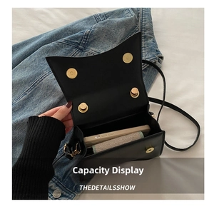 Close-up of black crossbody bag interior capacity with double golden magnetic clasps