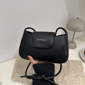 Minimalist black matte leather underarm bag with thin shoulder strap and front flap logo