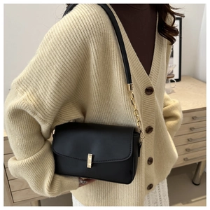 Detail of vintage black square bag featuring elegant gold metal lock and chain strap