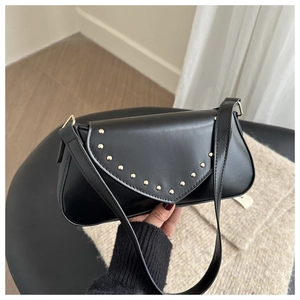 Detailed macro view of black crescent bag with golden rivets and metallic ring details