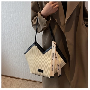 Close-up of cream pleated tote bag featuring black slim straps and textured vertical ribs