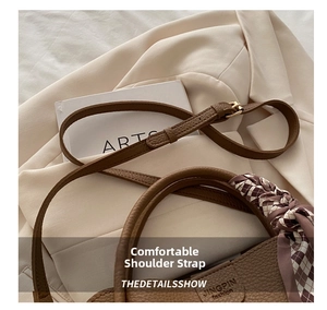 Detail of adjustable leather strap and silk scarf handle on brown litchi pattern bucket bag