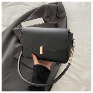 Close-up of black leather handbag with gold twist lock and elegant chain shoulder strap