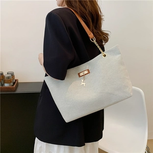 Chic light gray canvas tote bag with chain strap and deer pendant in a side view