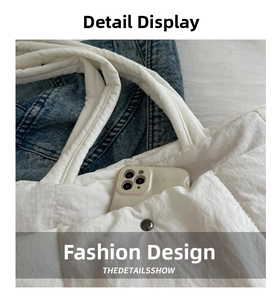 Detail of white quilted tote bag outer pocket showing mobile phone storage functionality
