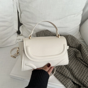 Chic cream white small square handbag with curved stitching and gold hardware