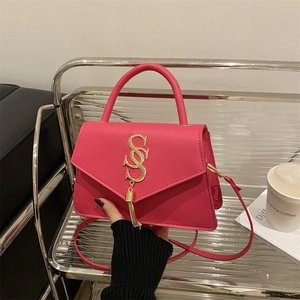 Magenta faux leather handbag with gold S-logo and metal tassel on modern display stand