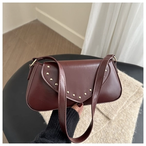 Detail view of burgundy leather bag with golden rivets and elegant flap closure