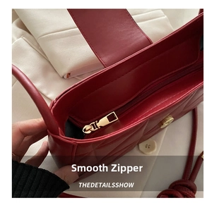 Detail of red quilted shoulder bag featuring smooth golden zipper and magnetic closure
